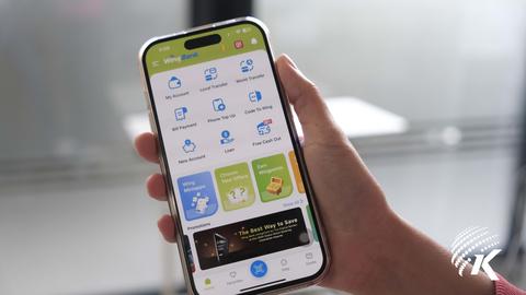 The photo shows a person holding a phone displaying the interface of the Wing Bank app. Kiripost/Vann Chanthada